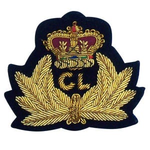 May include: A navy blue embroidered patch featuring a gold crown and laurel leaves. The crown is red and gold, with the initials "CL" in gold thread. The patch has a unique shape, with a dark blue border.