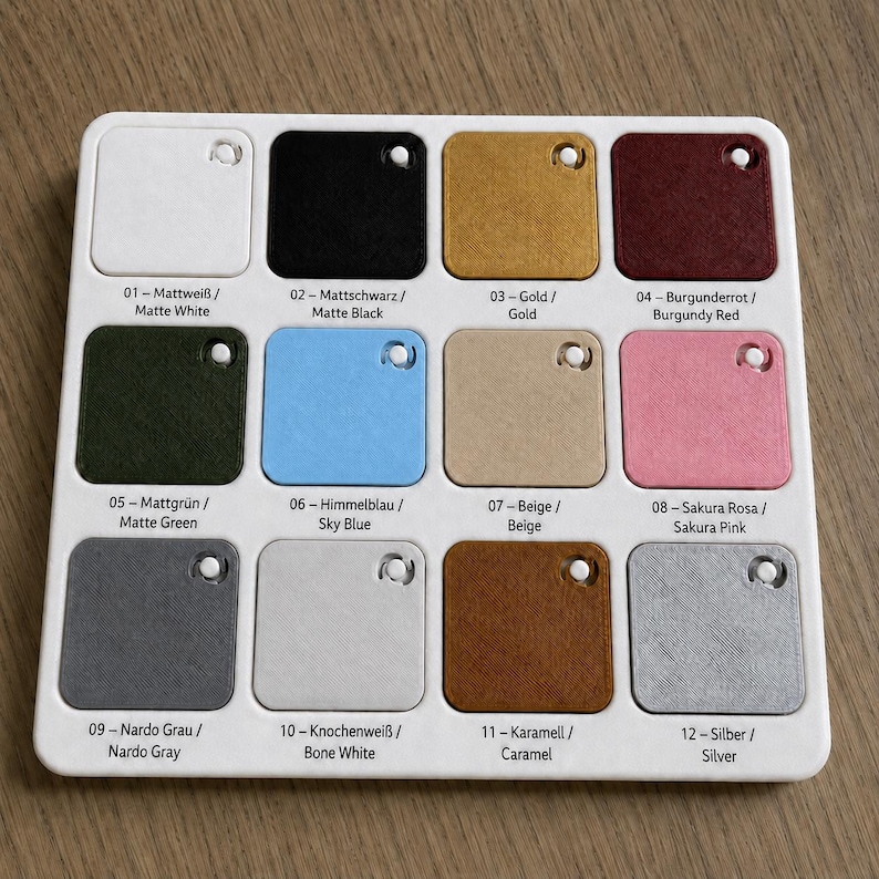 May include: A white plastic color palette featuring twelve color swatches. The swatches include matte white, black, gold, burgundy red, matte green, sky blue, beige, sakura pink, nardo gray, bone white, caramel, and silver. Each swatch has a small hole.