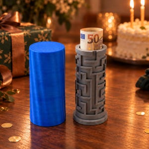 May include: A cylindrical blue container and a grey puzzle box with a maze pattern on its exterior. The grey puzzle box contains a rolled-up 50 Euro banknote visible at the top. Both items are cylindrical in shape and stand upright.