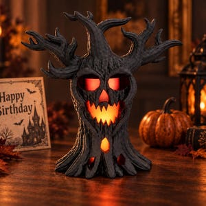May include: A dark gray, textured tree-shaped sculpture with a hollowed-out face featuring jagged, glowing orange eyes and a mouth. The tree has gnarled, spreading branches and a wide, flared base, emitting a warm light from within its carved openings.