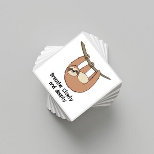 May include: A stack of white square cards with a cartoon sloth hanging from a branch. The sloth is brown with a beige belly. The text "Breathe slowly and deeply" is printed in black on the cards.