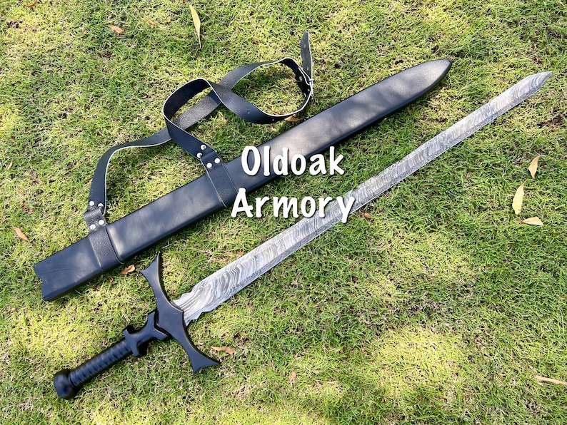 May include: A sword with a patterned blade and black handle, lying on green grass next to a black sheath. The sword has a crossguard and a rounded pommel. The text "Oldoak Armory" is visible.