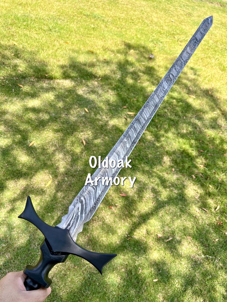 May include: A long, ornate sword with a patterned blade and a black handle and crossguard. The text "Oldoak Armory" is visible on the blade. The sword is held against a backdrop of green grass.