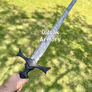 May include: A long, ornate sword with a patterned blade and a black handle. The sword is held against a backdrop of green grass. The text "Oldoak Armory" is visible on the blade.