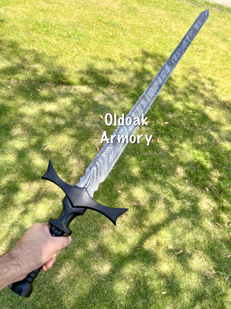 May include: A long, ornate sword with a patterned blade and a black handle. The sword is held against a backdrop of green grass. The text "Oldoak Armory" is visible on the blade.