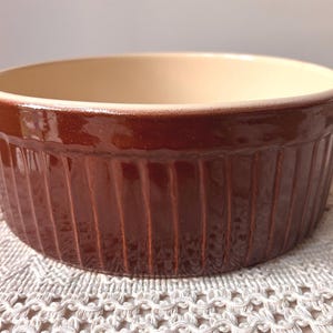 May include: A set of three ceramic mugs with a speckled, matte finish in cream, light brown, and dark brown. Each mug has a simple design and a rounded handle.