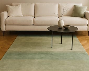 Pode incluir: Uma sala de estar moderna com um sofá creme, uma mesa de centro redonda preta e um tapete verde degradê. Um vaso com galhos e uma tigela estão sobre a mesa. Uma pintura está pendurada na parede.