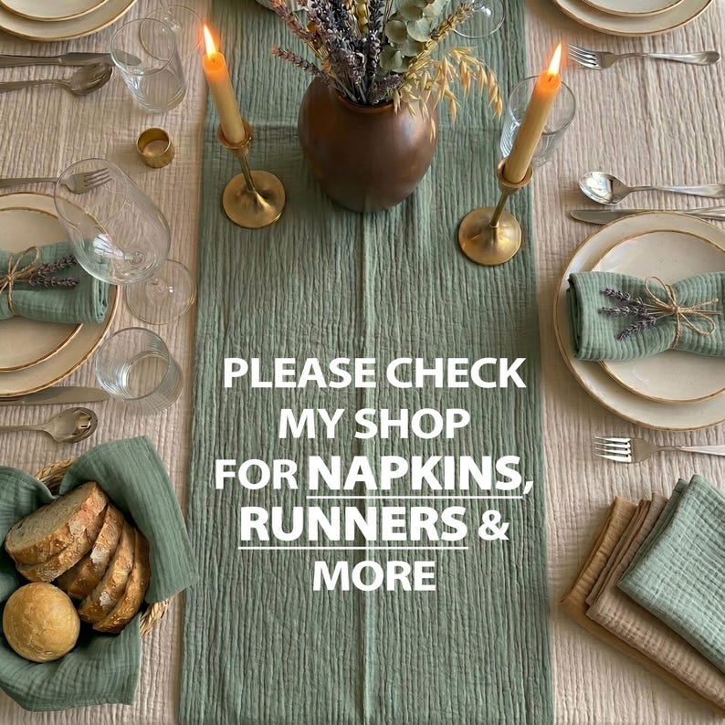 May include: A table setting with a green table runner, plates, silverware, and glasses. The centerpiece includes a vase with dried flowers and two lit candles in gold holders. The text on the runner reads: "PLEASE CHECK MY SHOP FOR NAPKINS, RUNNERS & MORE."