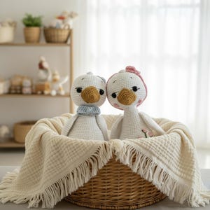 Alt Text: The amigurumi crochet goose doll couple nestled comfortably in a wicker basket lined with a soft muslin blanket. A heartwarming baby shower gift or newborn present.
