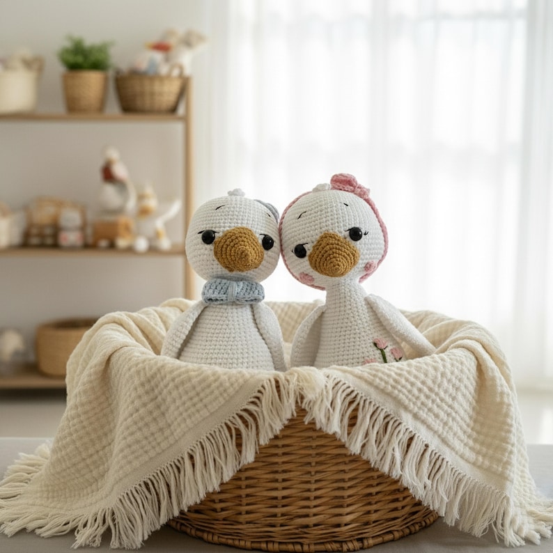 Alt Text: The amigurumi crochet goose doll couple nestled comfortably in a wicker basket lined with a soft muslin blanket. A heartwarming baby shower gift or newborn present.
