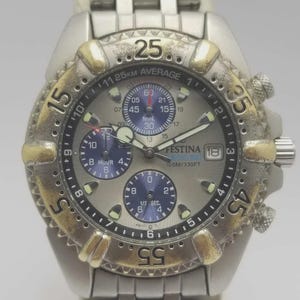 Peut inclure: Montre Festina argentée avec cadran gris et détails dorés sur la lunette. Bracelet en acier inoxydable. Le cadran affiche plusieurs sous-cadrans et la date. Résistante à l'eau jusqu'à 100 mètres.