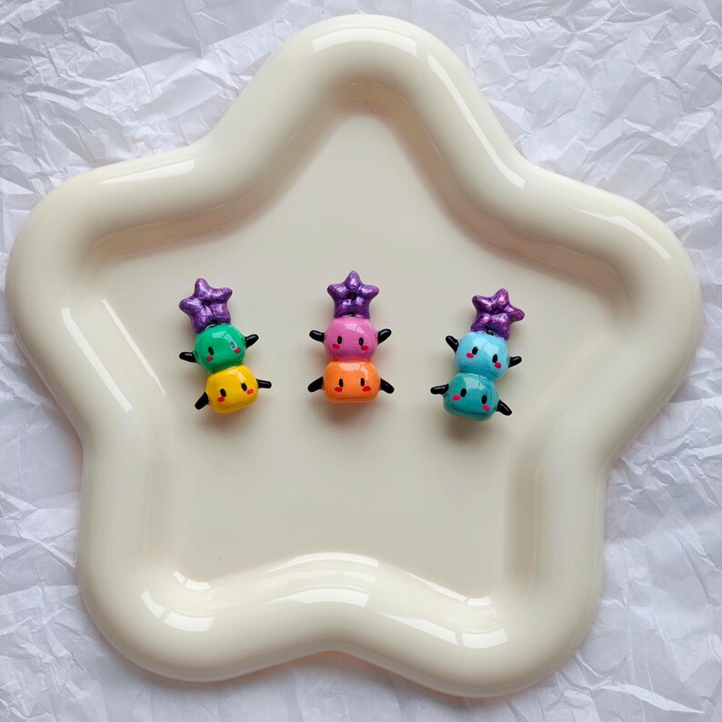 K&ouml;nnte beinhalten: Ein Set aus drei Keramikbechern mit gesprenkelter, matter Oberfl&auml;che. Jeder Becher hat eine andere Farbe: hellblau, cremefarben und grau. Die Becher haben ein schlichtes, modernes Design und einen bequemen Griff.