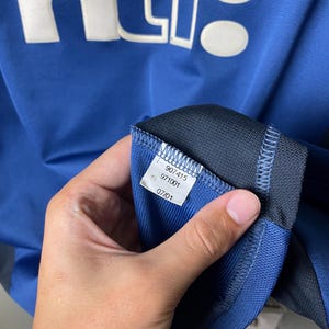 May include: A blue athletic jersey featuring the white text ntl: printed on the front. An interior white fabric tag is visible, displaying the numbers 907415, 971001, and the date 07/01. The garment is constructed from a textured, breathable material.