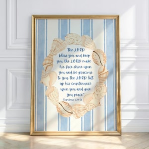 May include: A framed print featuring a watercolor design with a gold frame. The artwork displays a blue and white striped background with a seashell wreath surrounding a quote from Numbers 6:24-26. The text is in a blue script font.