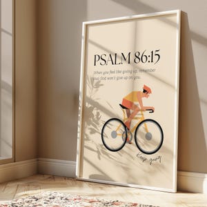 Könnte beinhalten: Gerahmter Kunstdruck mit einem Radfahrer auf einem gelben Fahrrad. Das Kunstwerk enthält den Text "PSALM 86:15" und das Zitat "Wenn du das Gefühl hast aufzugeben, erinnere dich daran, dass Gott dich nicht aufgeben wird." Die Worte "Keep going" sind ebenfalls enthalten.
