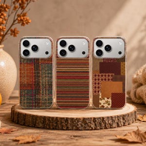 May include: Three smartphone cases featuring distinct autumn-inspired patterns. The left case has a multicolored plaid design, the center case displays horizontal stripes in warm tones, and the right case shows a patchwork of various fall prints.