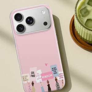 Puede incluir: Una funda de smartphone rosa claro con una ilustraci&oacute;n gr&aacute;fica de varias manos levantadas sosteniendo carteles de protesta. Los carteles muestran texto que incluye GRL PWR, WOMEN CAN y WE HAVE THE RIGHT TO BE HEARD, con un peque&ntilde;o coraz&oacute;n rosa.