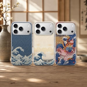 May include: Three smartphone cases featuring Japanese-inspired art. The left case has a blue wave pattern, the center case displays a classic wave illustration, and the right case depicts a figure riding a large pink fish amidst ocean waves.