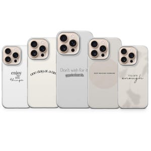Peut inclure: Cinq coques de téléphone avec des citations inspirantes dans un style minimaliste. Les coques sont blanches ou blanc cassé, avec des phrases comme "Profitez des petites choses" et "Ne le souhaitez pas, travaillez-y".