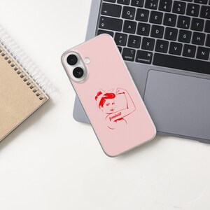 Puede incluir: Una funda de smartphone de color rosa claro con una ilustraci&oacute;n gr&aacute;fica roja de una persona flexionando el brazo con la palabra feminist escrita en cursiva. La funda tiene dos aberturas circulares para las lentes de la c&aacute;mara.