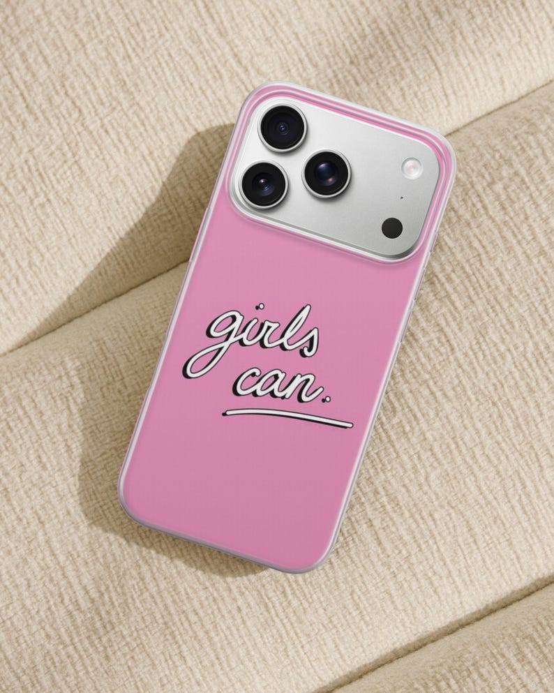 Puede incluir: Una funda de smartphone rosa con el texto "girls can." en una fuente cursiva blanca con borde negro. La funda tiene un borde transparente y est&aacute; dise&ntilde;ada para un tel&eacute;fono con un sistema de triple c&aacute;mara y flash visible en la parte posterior.