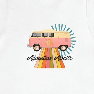 May include: White t-shirt with a pink and yellow vintage van driving on a rainbow road with the text "Adventure Awaits".
