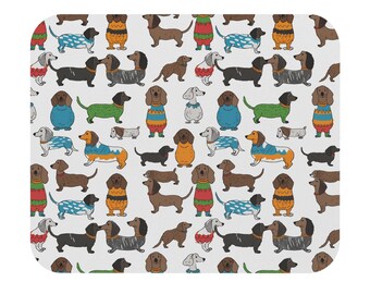 Puede incluir: Alfombrilla de ratón rectangular con un patrón repetido de perros salchicha de dibujos animados. Los perros están en varias poses y colores, algunos con suéteres. El fondo es blanco.