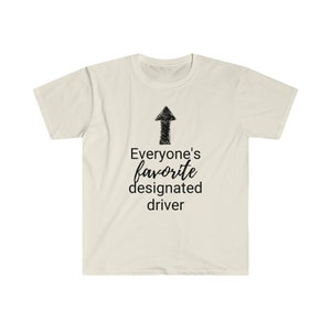 May include: A cream-coloured t-shirt featuring the text "Everyone's favourite designated driver" in black script, with a black arrow pointing upwards. The shirt is made of a soft, lightweight material.