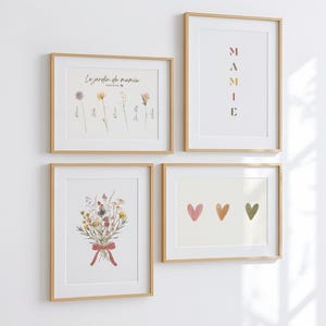 Op de afbeelding: Vier ingelijste kunstdrukken met houten frames worden op een witte muur getoond. De prints bevatten botanische illustraties, de tekst "La jardin de mamie", het woord "MAMIE" en drie harten in roze, oranje en groen.