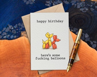 Könnte beinhalten: Eine Geburtstagskarte mit dem Text „Happy Birthday“ und „here's some fucking balloons“. Die Karte zeigt Illustrationen von gelben und roten Ballonfiguren. Auf der Seite liegt ein brauner und goldener Füllfederhalter.