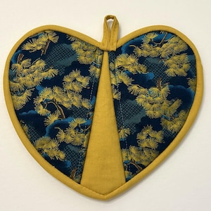 May include: Heart-shaped quilted potholder with a navy blue and gold pine tree pattern. The potholder has a yellow border and a yellow center panel. A small yellow loop is at the top for hanging.