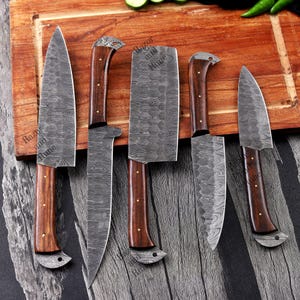 May include: A set of five Damascus steel kitchen knives with wooden handles. The blades have a unique patterned design. The handles are a dark brown color with brass rivets. The knives are arranged on a wooden cutting board.