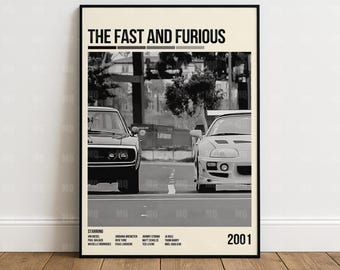 May include: Black and white framed poster for "The Fast and Furious" movie. The poster features two cars facing each other on a road. The movie title is at the top, with the year 2001 at the bottom. The poster also lists the starring actors.