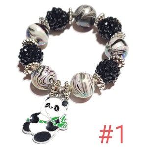 May include: A black and white panda charm bracelet with black and white swirl beads and black rhinestone beads. The bracelet has a silver charm of a panda holding a bamboo stalk. The bracelet is labeled #1.