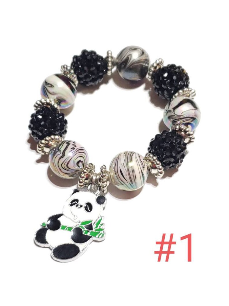 May include: A black and white panda charm bracelet with black and white swirl beads and black rhinestone beads. The bracelet has a silver charm of a panda holding a bamboo stalk. The bracelet is labeled #1.