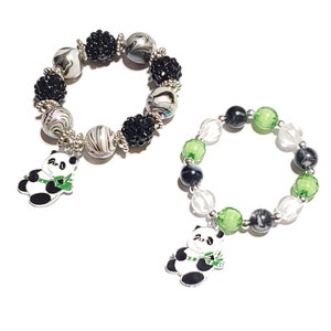 May include: Two panda charm bracelets. One bracelet has black and white swirl beads with black rhinestone accents. The other bracelet has clear, green, and black beads. Both bracelets have a panda charm.