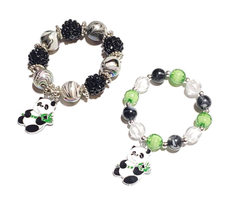 May include: Two panda charm bracelets. One bracelet has black and white swirl beads with black rhinestone accents. The other bracelet has clear, green, and black beads. Both bracelets have a panda charm.