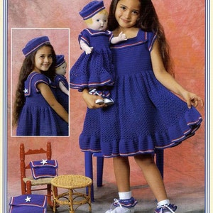 May include: Two girls wearing blue and white crocheted dresses and matching hats. The girls are holding a doll wearing a similar dress and hat. The image includes the text "Anchors Aweigh".