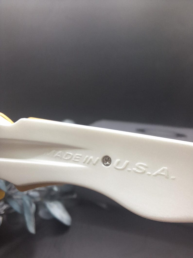 May include: Close-up of a cream-colored plastic object with the text "MADE IN U.S.A." stamped on its surface. The object has a curved shape and appears to be part of a larger item.