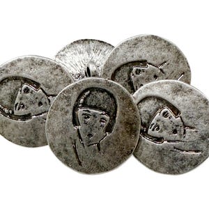 May include: A collection of antique silver-toned metal buttons. Each button features a unique embossed design, including stylized faces and abstract shapes. The buttons have a weathered appearance, suggesting age and use.