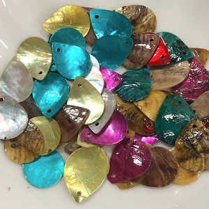 May include: A collection of teardrop-shaped shell charms in a variety of colors including turquoise, red, magenta, yellow, brown, and iridescent white. Each piece features a small pre-drilled hole at the top for threading or attachment.