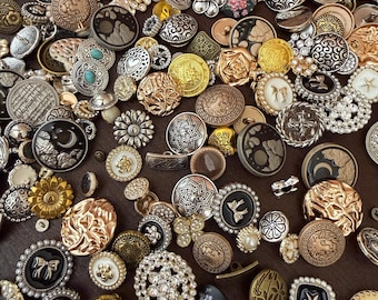 May include: A large collection of assorted decorative buttons in various shapes, sizes, and metallic finishes including gold, silver, bronze, and black. The buttons feature intricate embossed patterns, floral motifs, geometric designs, and embedded faux pearls.