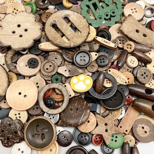 May include: A collection of various buttons in different shapes, sizes, and materials. The buttons are primarily in shades of brown, beige, and natural wood tones, with some featuring black, red, and green accents. Some buttons have text, and there is a yellow paw print button.