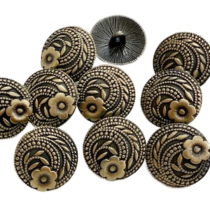 Könnte beinhalten: Eine Sammlung antiker, messingfarbener Knöpfe. Jeder Knopf hat ein Blumendesign mit einer zentralen Blume und wirbelnden Blättern. Die Knöpfe sind rund und haben eine detaillierte, strukturierte Oberfläche.