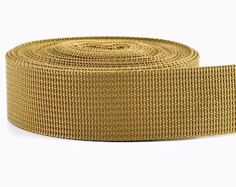 May include: A roll of tan-colored webbing material. The webbing is tightly woven and appears to be made of a durable, synthetic material. The roll is on a white background.