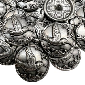 May include: A white ceramic mug with a black handle and the text "But First, Coffee" in a black, handwritten-style font. The mug is on a white surface.