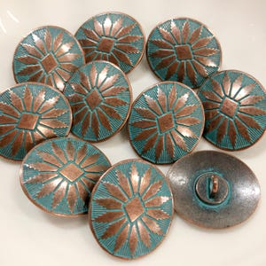 May include: A collection of round buttons featuring a copper-colored starburst pattern set against a recessed teal background. Each button has a central diamond shape surrounded by radiating rays and a shank on the back for attachment.