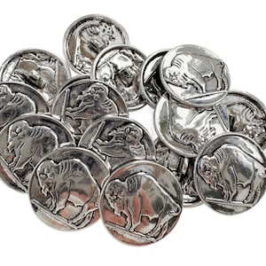 May include: A collection of silver-toned metal buttons. Some buttons feature a bison, while others depict a Native American profile. The buttons are round and have a slightly raised design. The buttons are scattered on a white background.