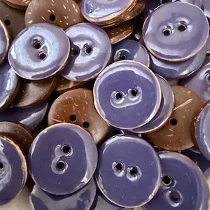 May include: A collection of round buttons in two styles. Some are a deep, glossy blue with two holes, while others are a natural brown with a textured surface. These buttons are suitable for sewing and craft projects.