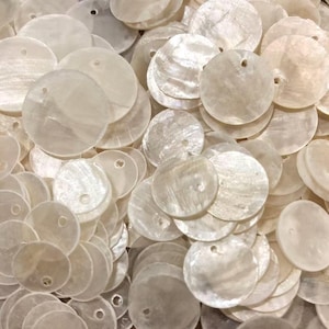 May include: A large collection of circular, off-white mother-of-pearl shell discs. Each individual disc features a smooth, iridescent surface with a natural pearlescent sheen and a single small hole punched near the top edge for threading.